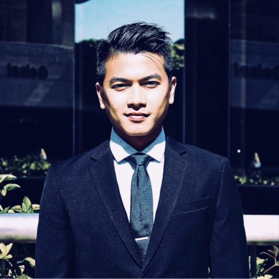 Adrian Mai, wearing a suit and tie outdoors.